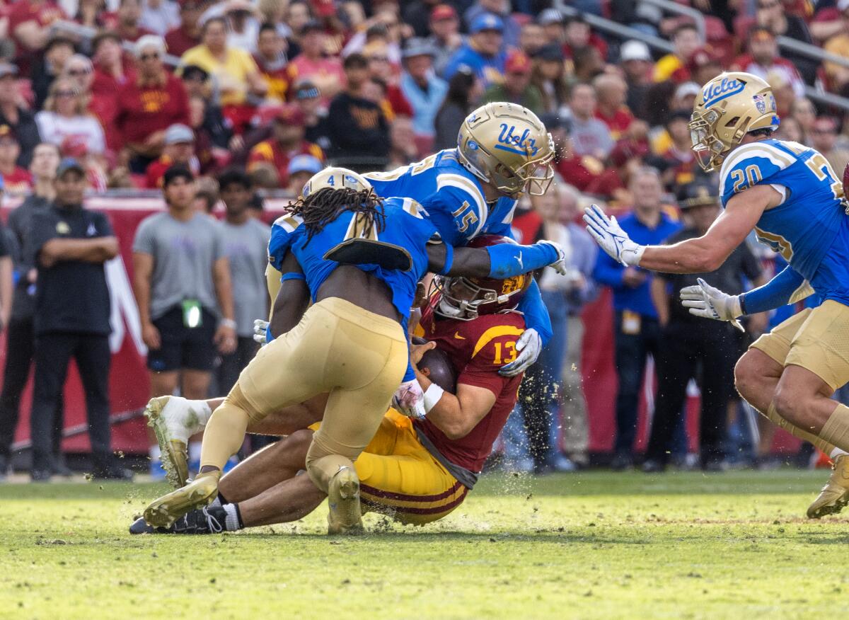 UCLA edge rushers Carl Jones Jr. (No. 4) and Laiatu Latu (top) sack USC quarterback Caleb Williams last season.