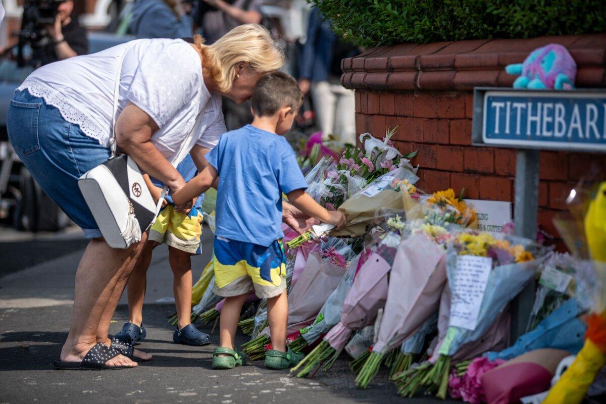 A child puts flowers on a pile of tributes near Hart Street in Southport, England, on July 30, 2024. (James Speakman/PA)