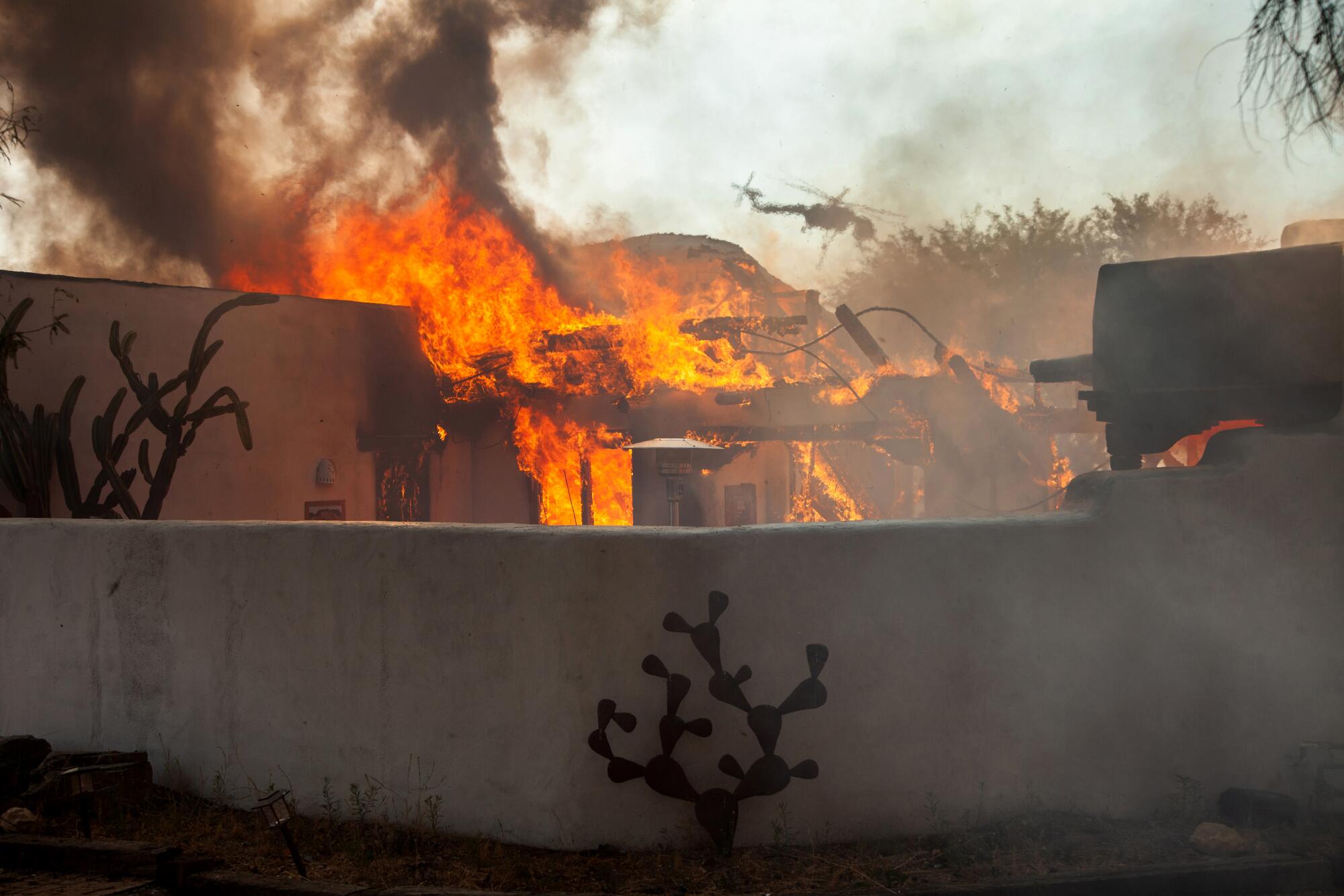 Fire fighters work to douse a home on fire in Harwarden Hills, a high-end living