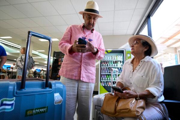 Jose Angel Saavedra, (L), and his wife Sara, of Johnston, Iowa, look at their cell phones while trying to book a flight after their original flight was cancelled, at the Des Moines International Airport in Des Moines, Iowa on July 19, 2024. (Charlie Neibergall/AP Photo)