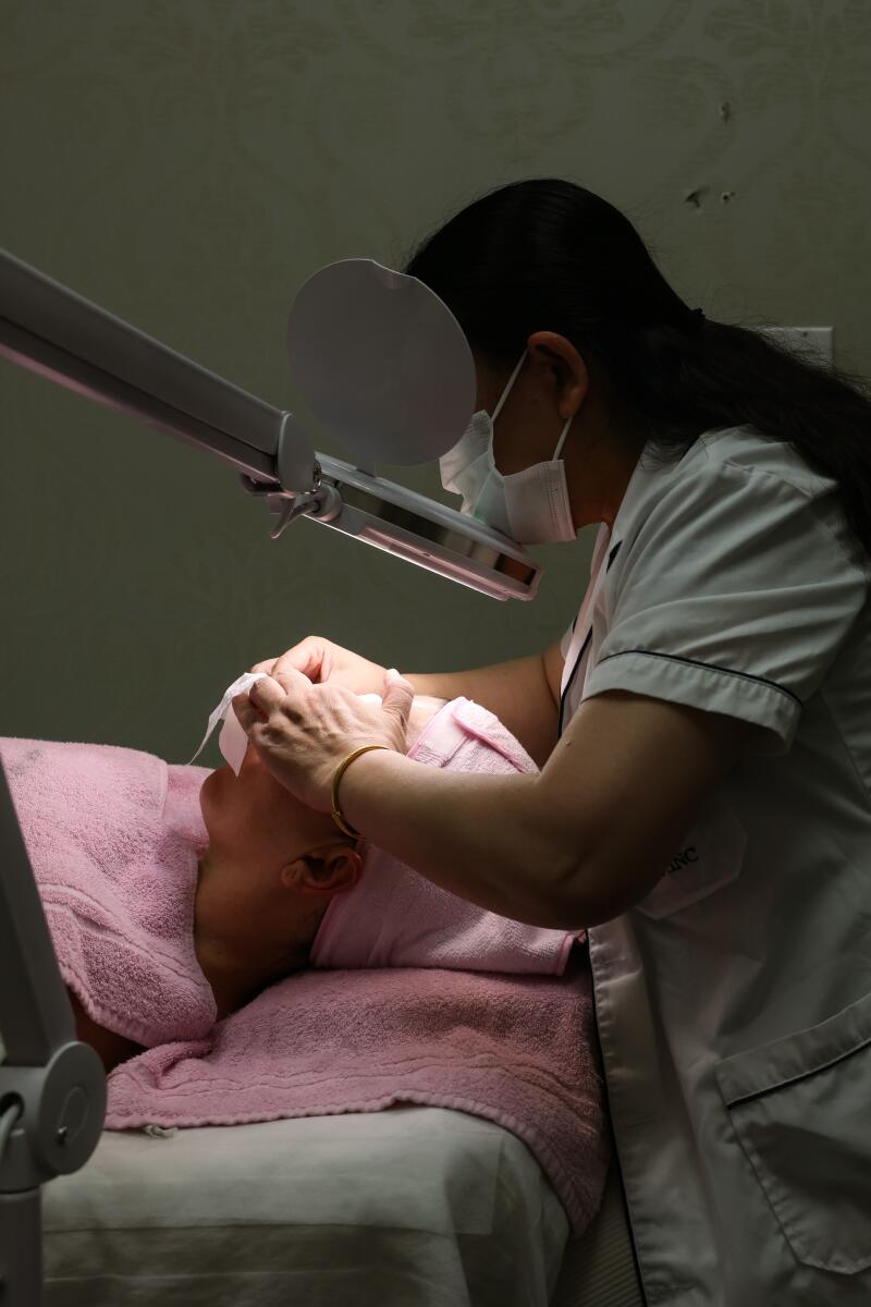 Yajing Lu does extractions on Jackie Snow's face.