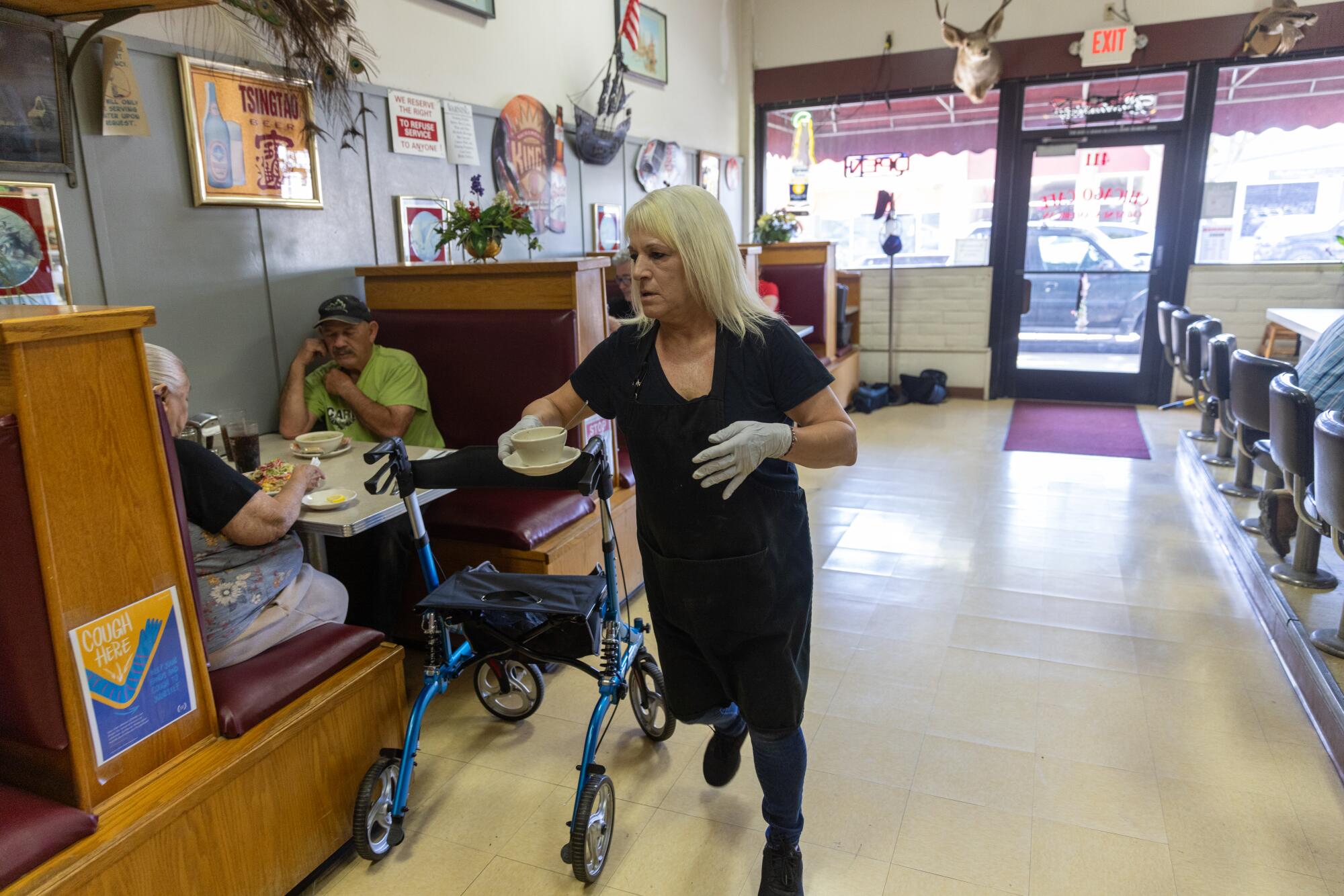 A busy waitress delivers a bowl of food to a table. 