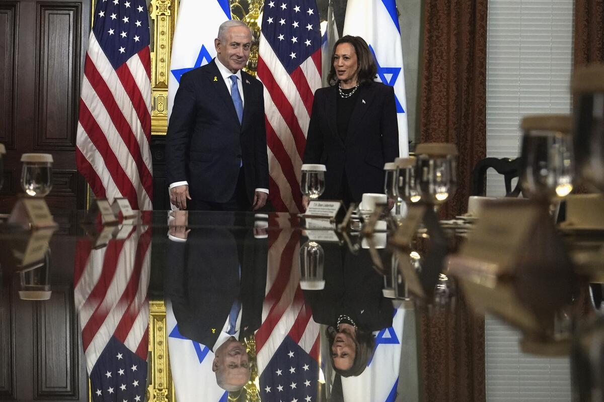 Benjamin Netanyahu and Kamala Harris stand before a large table 