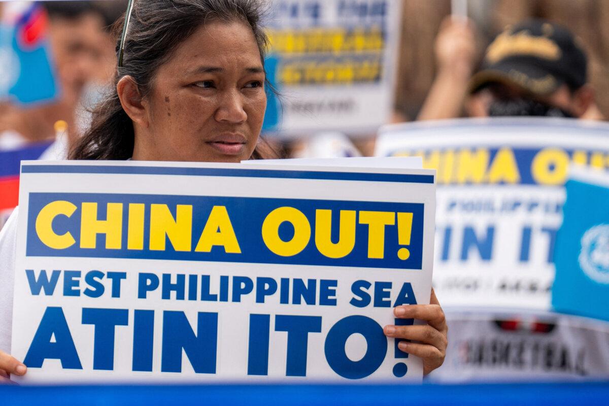 A woman holds a placard during a protest marking the 8th anniversary of the 2016 arbitration ruling over China's claims in the South China Sea, in Quezon City, Philippines, July 12, 2024. (Lisa Marie David/Reuters)