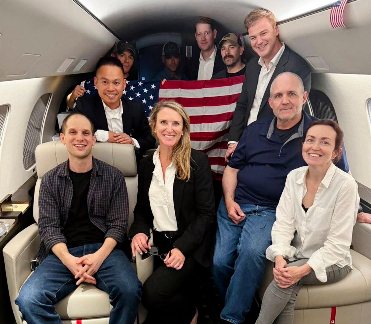 This image released by the White House shows Evan Gershkovich, left, Alsu Kurmasheva, right, and Paul Whelan, second from right, and others aboard a plane on Aug. 1, 2024, following their release from Russian captivity. (White House via AP)