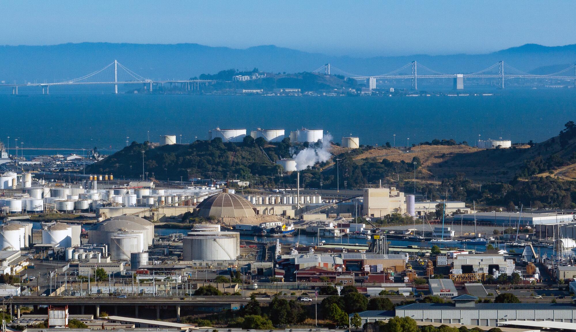 An aerial view of a refinery with a bridge in the distance.