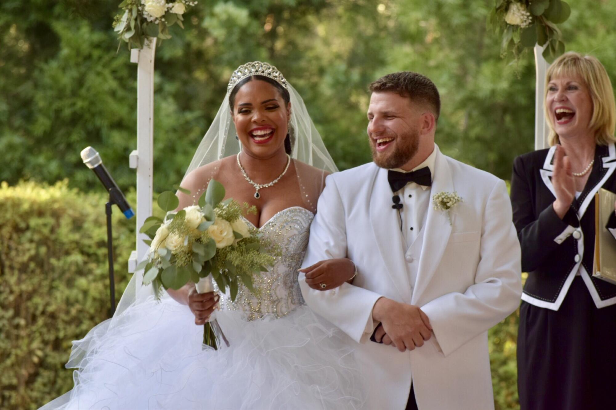 A bride holds a bouquet in one hand and her groom's arm with the other