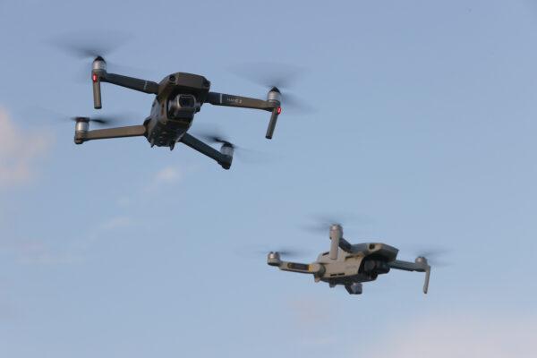 A DJI Mavic 2 Pro and DJi Mavic Mini made by the Chinese drone maker fly near each other in Miami, Fla., on Dec. 15, 2021. (Joe Raedle/Getty Images)