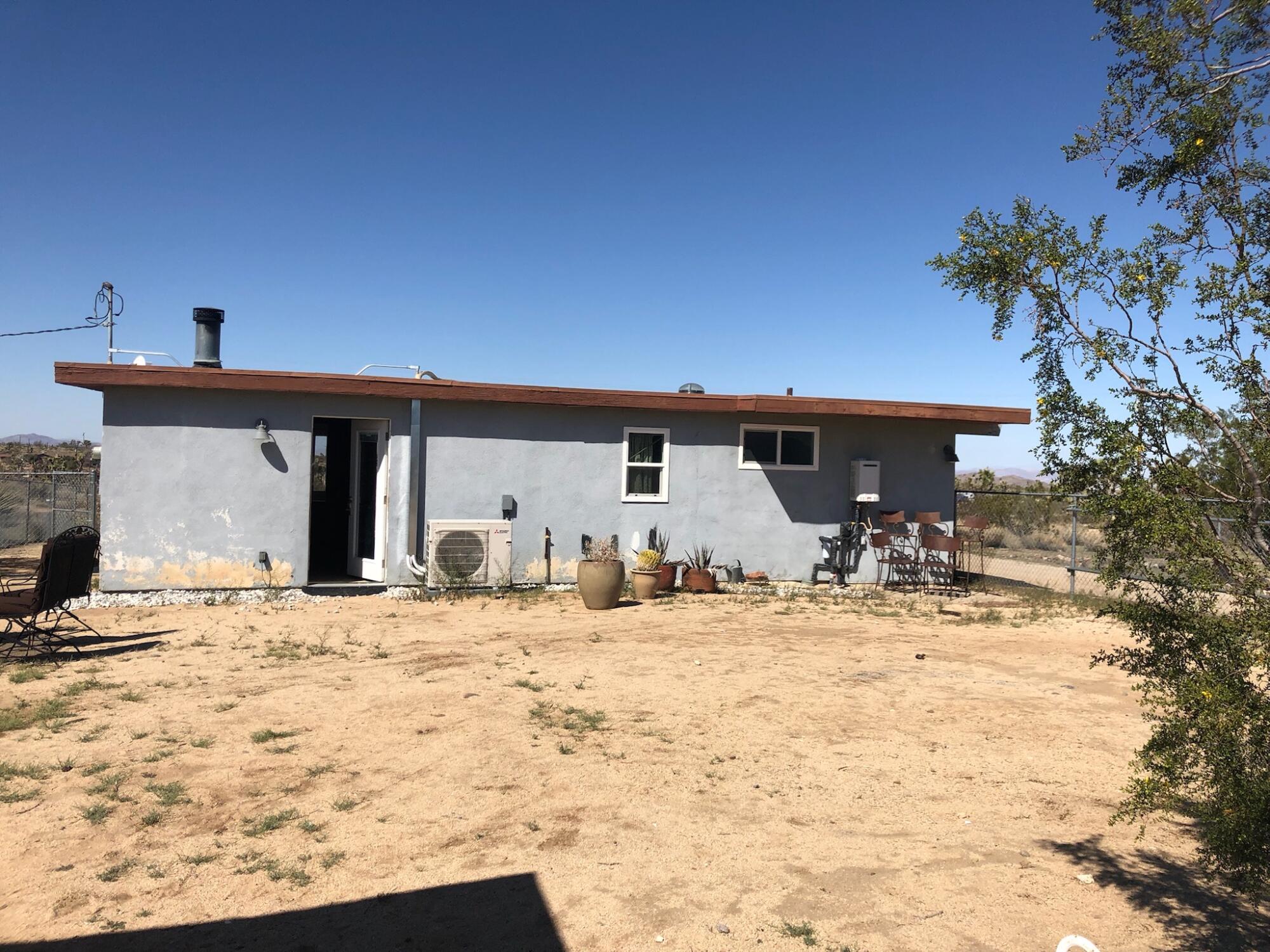 A light blue rundown house and desert landscape