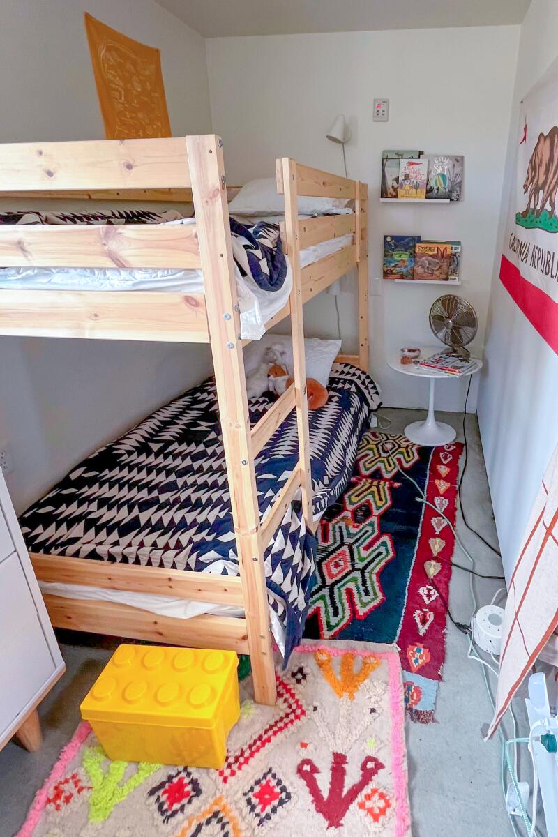 A narrow room with bunk beds and colorful rugs