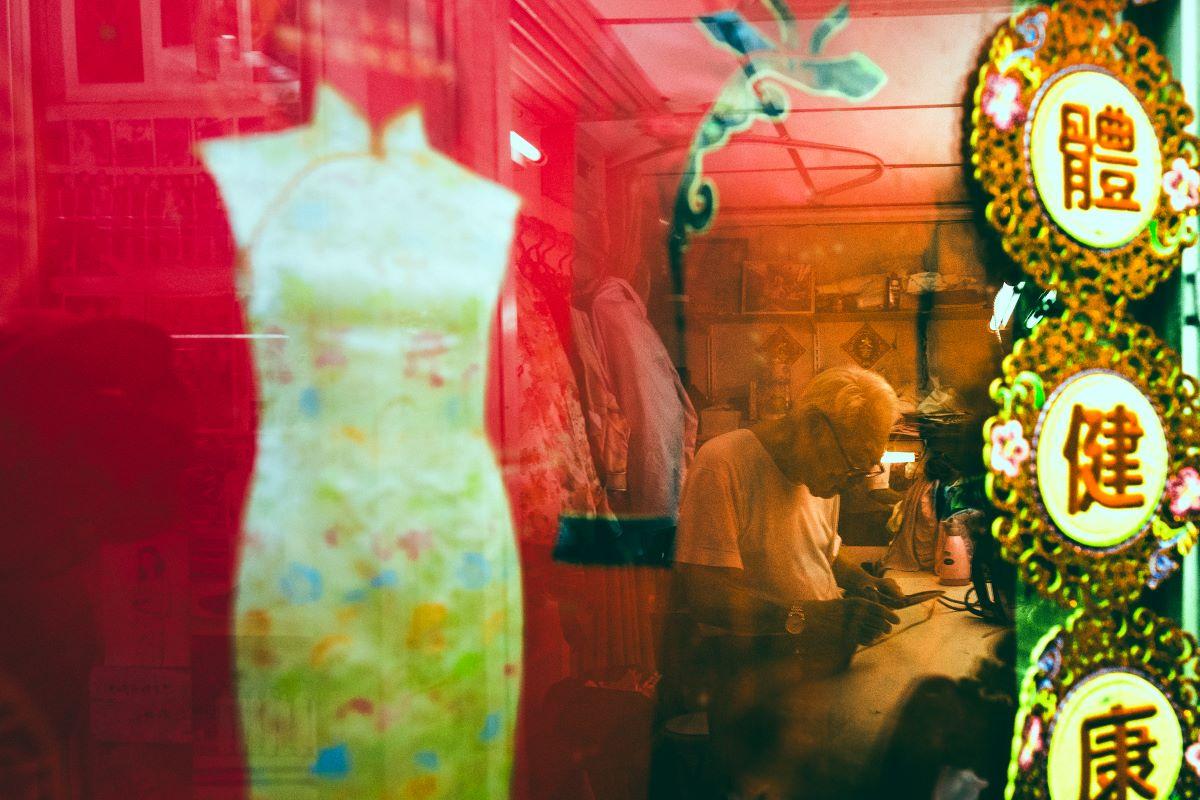 A Cheongsam on display with Master Yan in the background. (Lau Wing-hong/The Epoch Times)