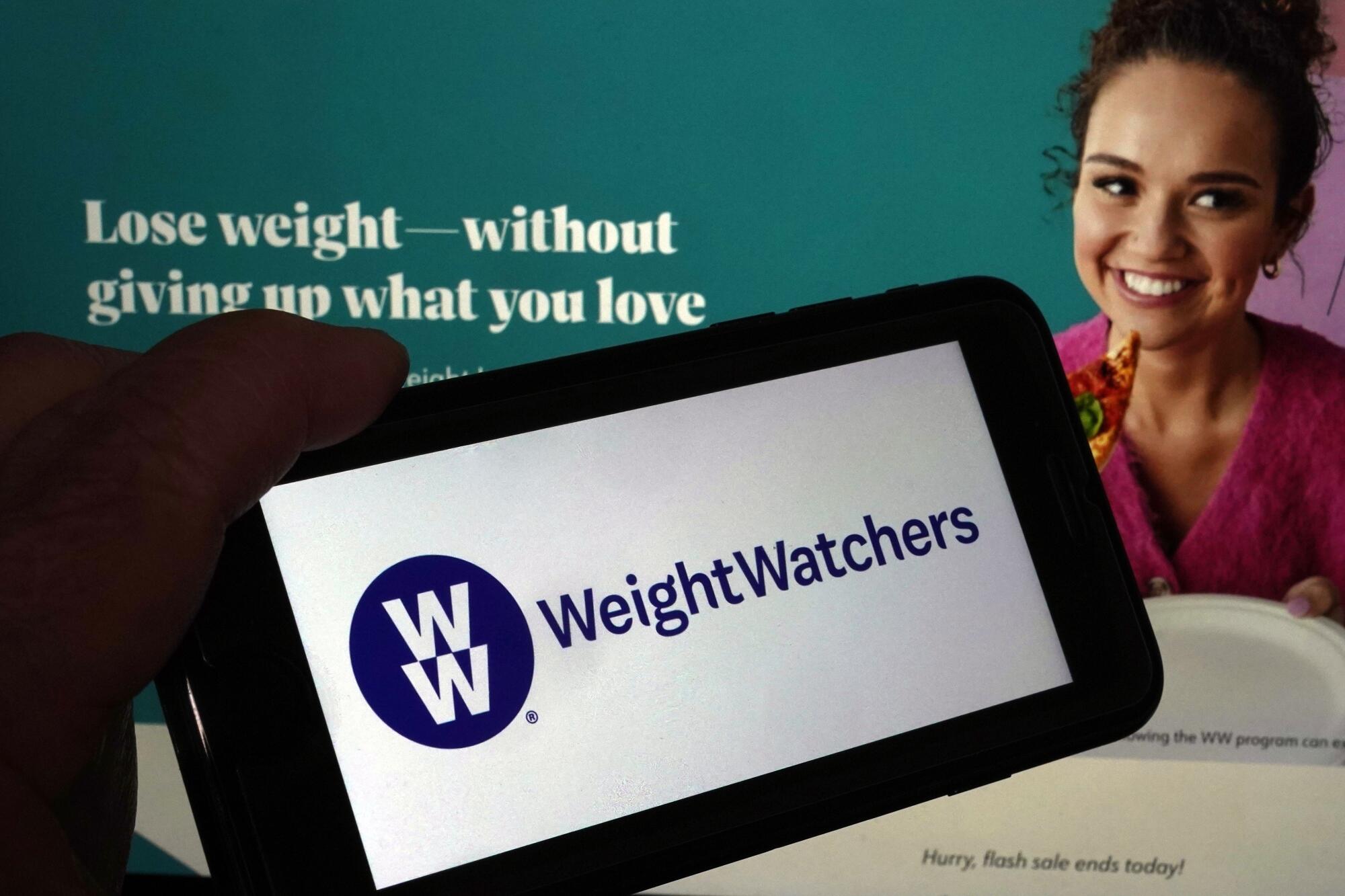 Logo of WeightWatchers on a mobile phone, and the company's website, in 2023.