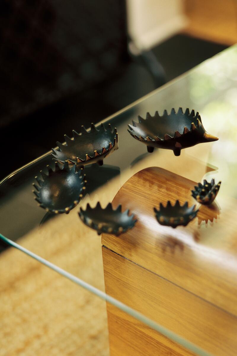 An ashtray that looks like a hedgehog, deconstructed into smaller hedgehog ashtrays, on a glass table.