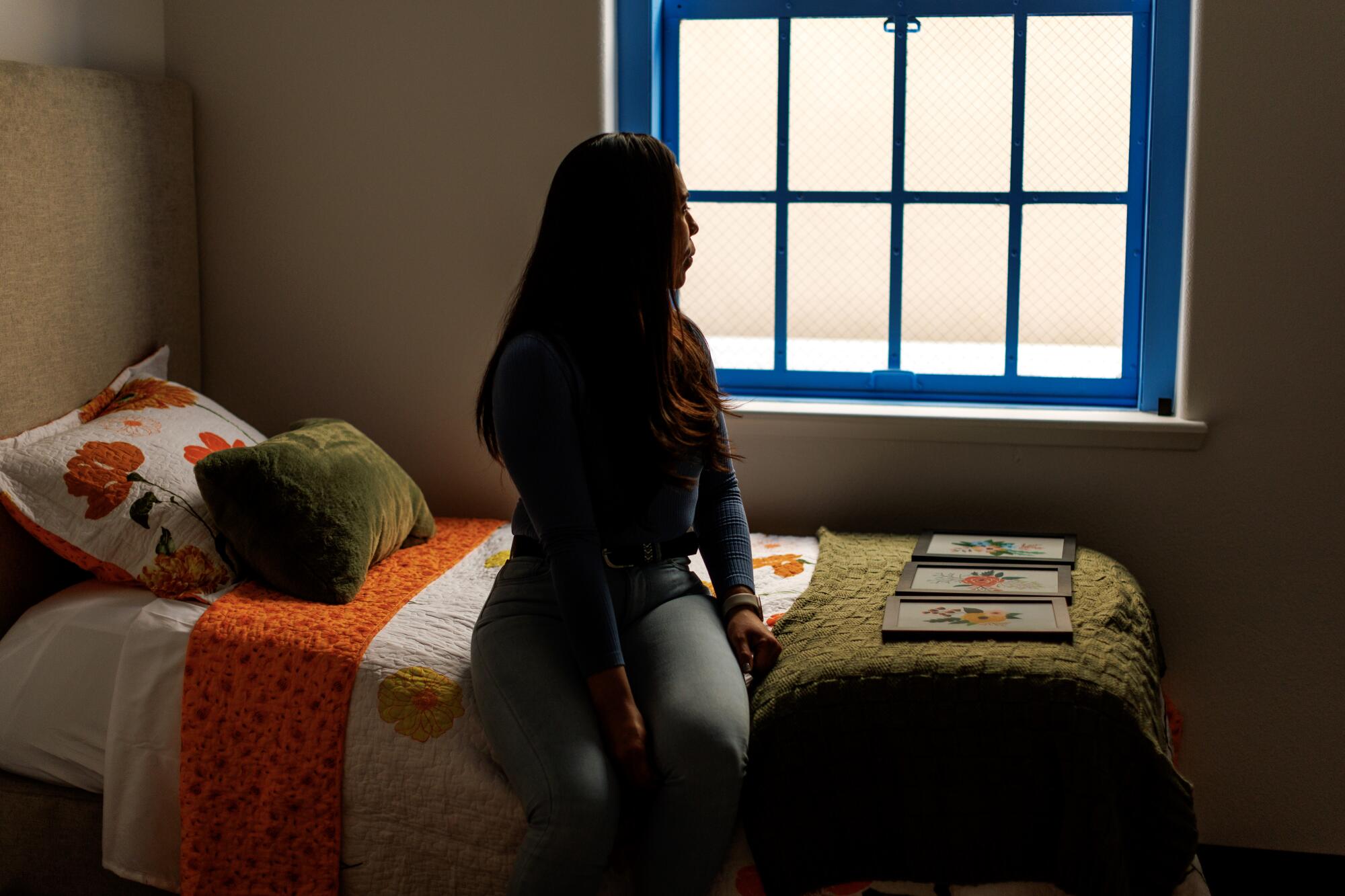 A woman stands next to a twin bed  