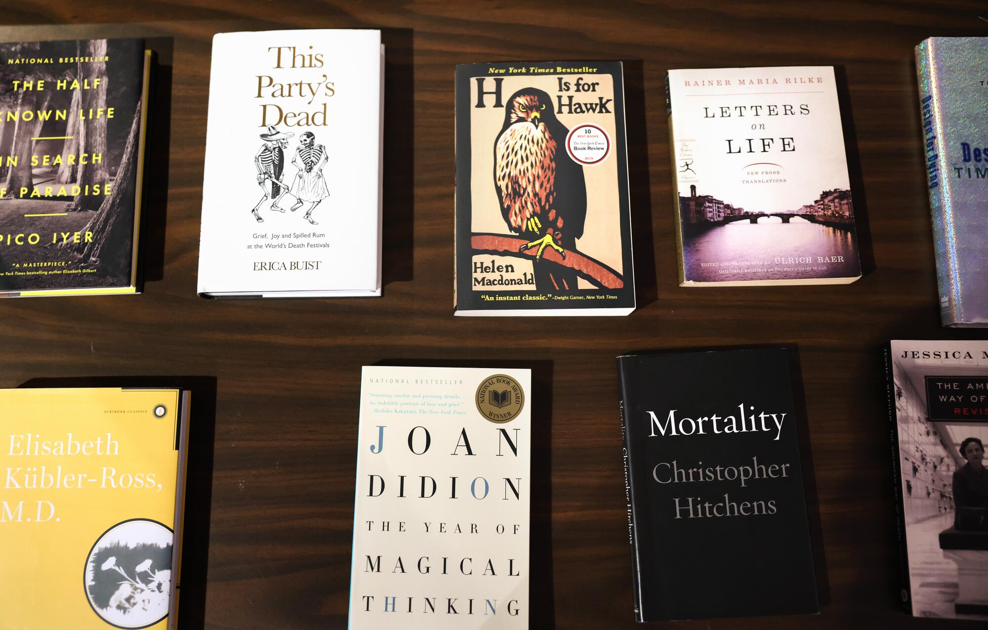 Books on a shelf including "Mortality" and "The Year of Magical Thinking"