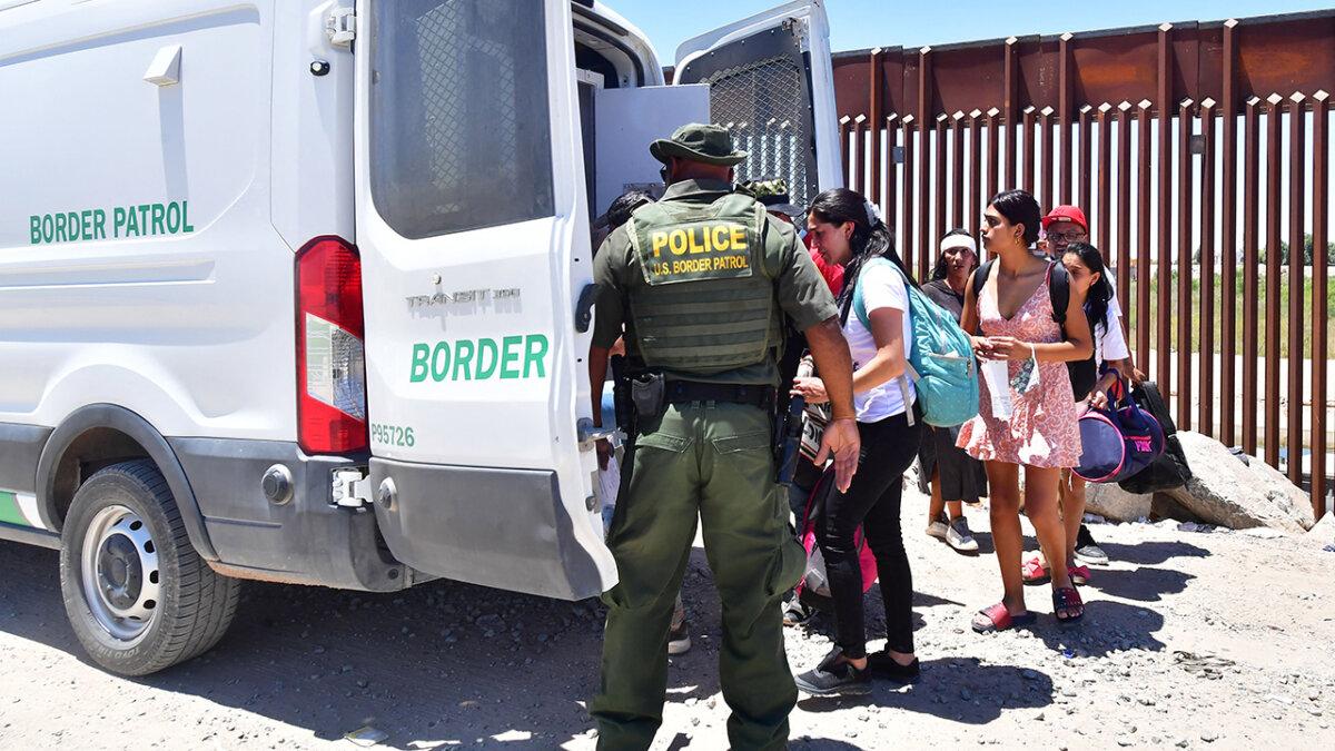 Immigrants board a U.S. Border Patrol van after crossing into the United States from Mexico through a gap in the border wall between Algodones, Mexico, and Yuma, Ariz., on May 16, 2022. (Frederic J. Brown/AFP via Getty Images)