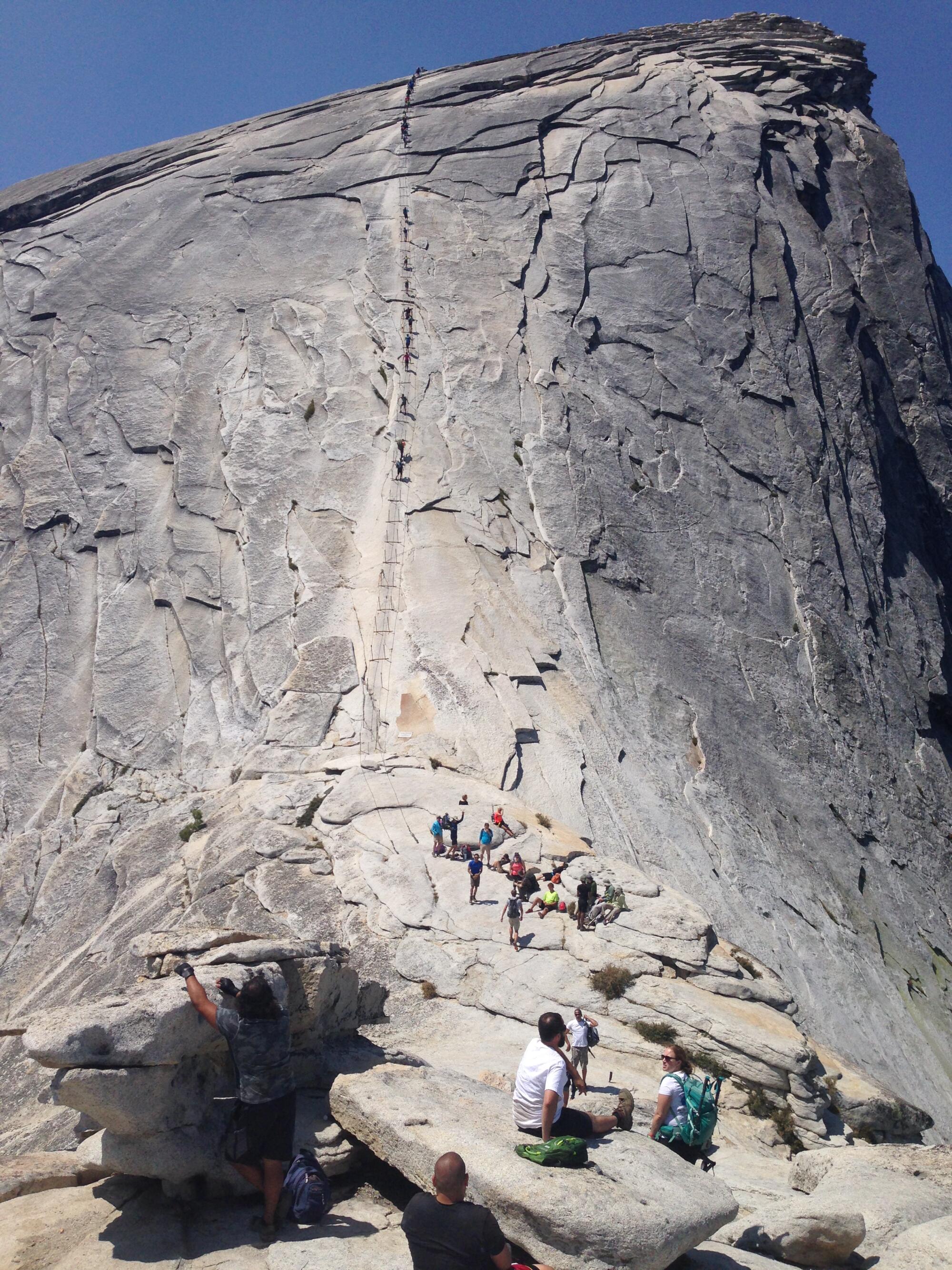 Hikers rest before attempting the metal cables that mark the steep final ascent to Half Dome's summit.