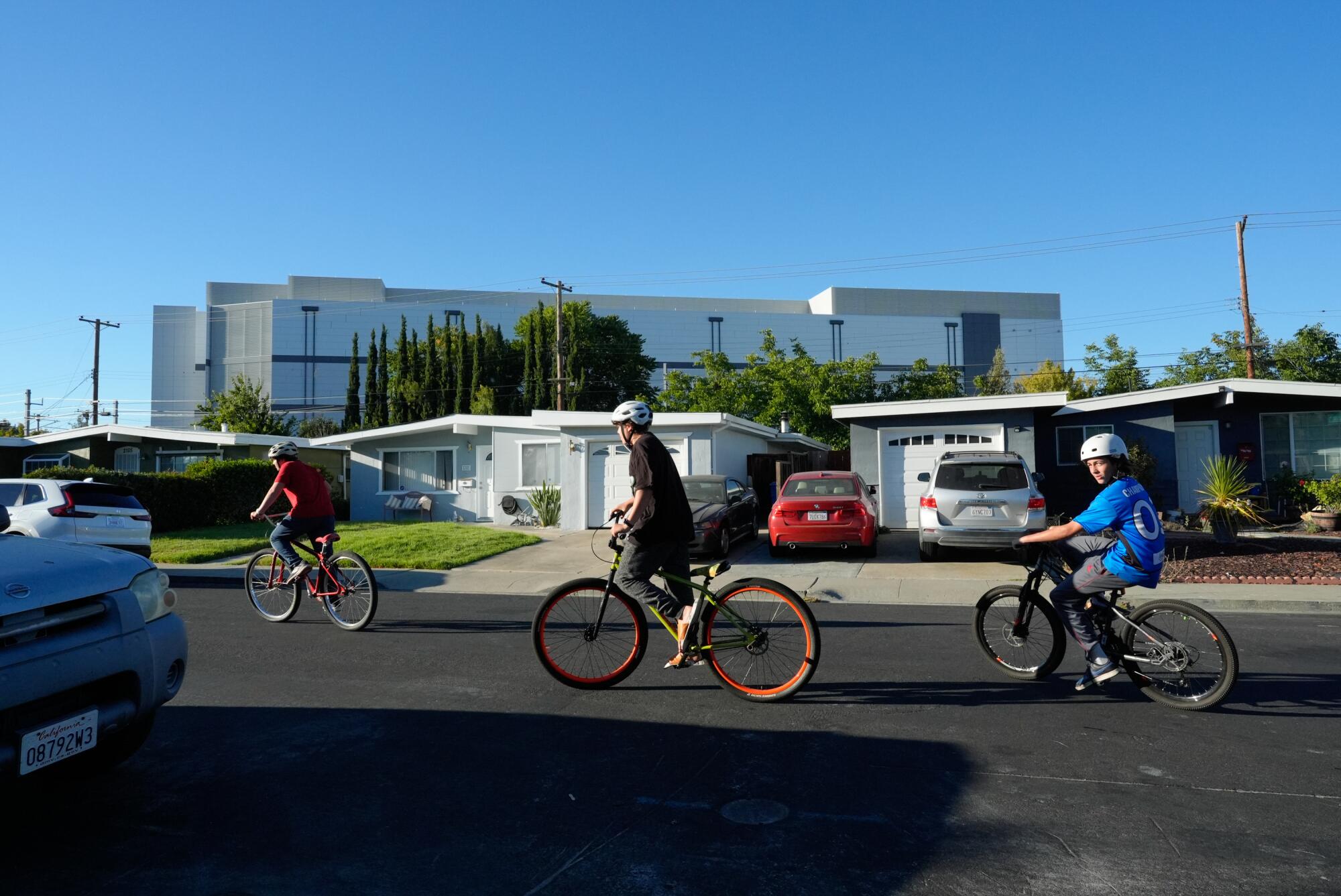 Boys ride their bikes on Main Street near a large data center in Santa Clara.