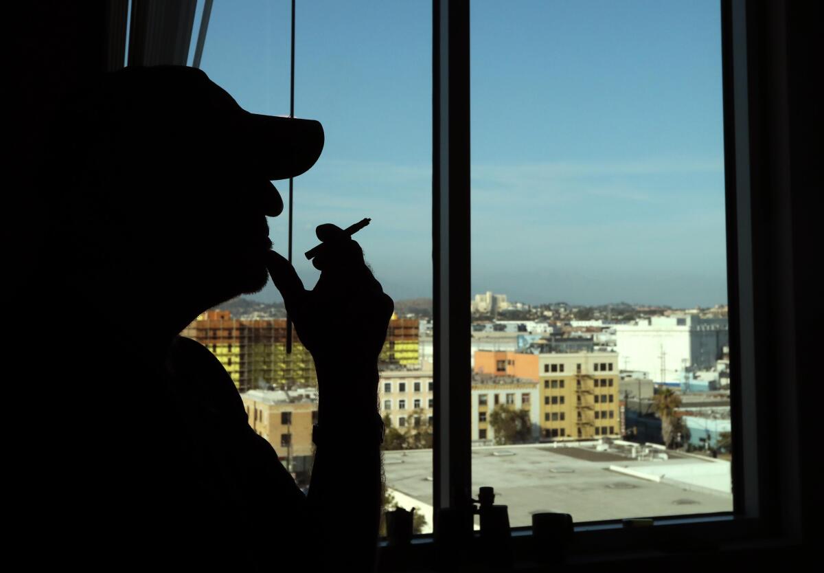 A man smokes and looks out a window.