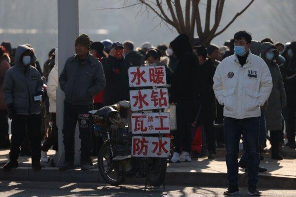 Migrant workers standing near signs advertising their skills as they wait by a street to be hired in Shenyang, in northeastern China's Liaoning province on Feb. 6, 2023. (STR/AFP via Getty Images)