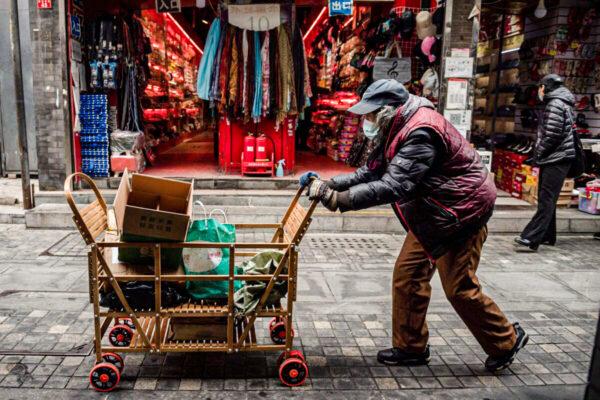 An elderly woman pushes a cart after searching through rubbish bins to collect recyclable items to sell, along a street near the Great Hall of the People in Beijing on March 5, 2021. (Nicolas Asfouri/AFP via Getty Images)