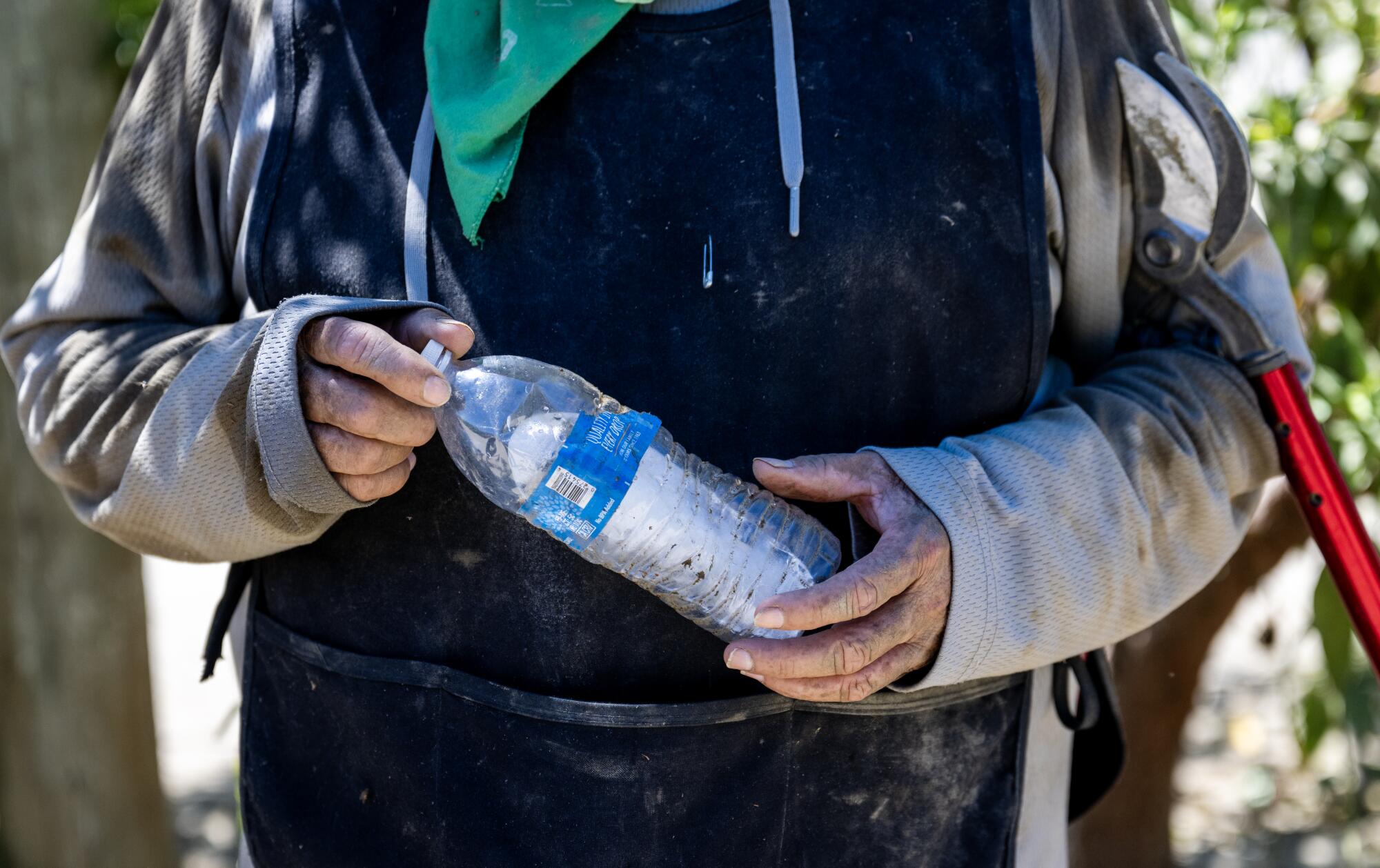 A farmworker holds a plastic bottle containing a chunk of ice.